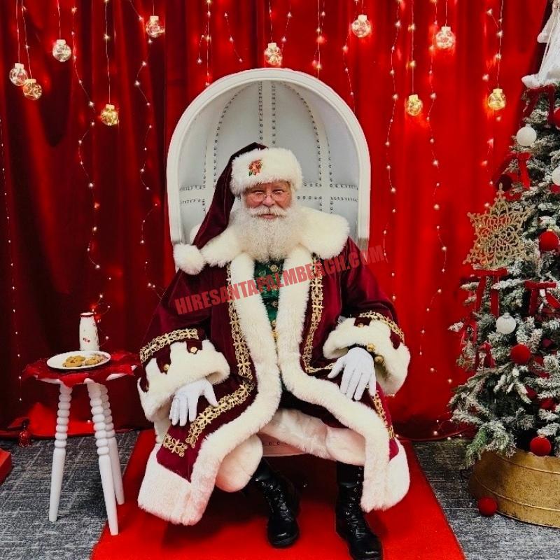 Real bearded Santa for hire in Palm Beach Gardens, FL in a white chair, cookies and milk at his side.