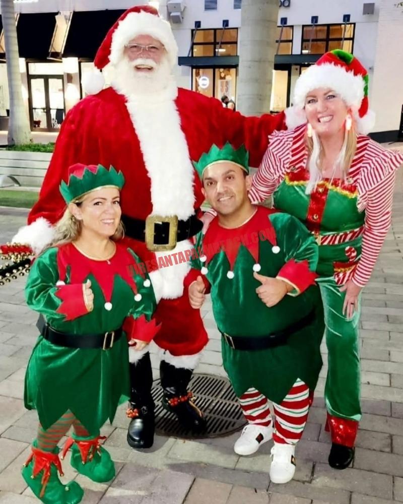 School Santa visit in Wellington, FL: Santa standing with three elves in green hats and costumes.