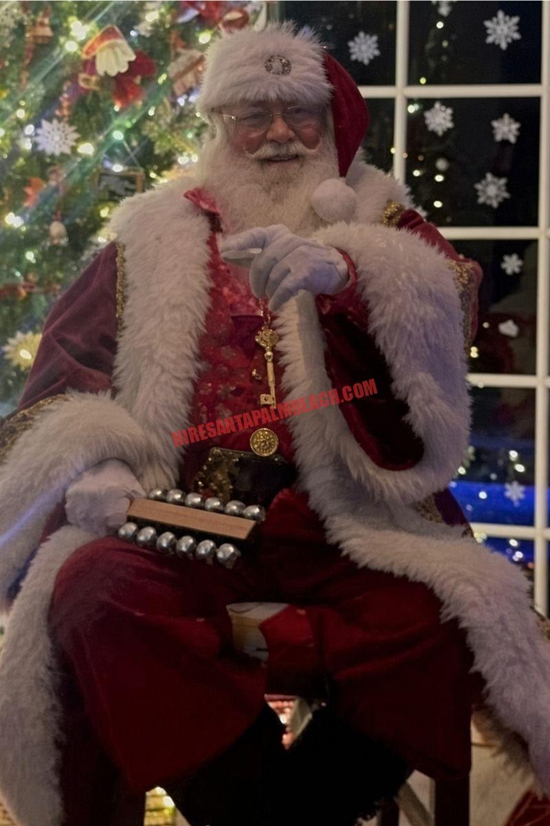 Santa house call in Jupiter, FL: Santa seated with sleigh bells, a gold key, and a night window.